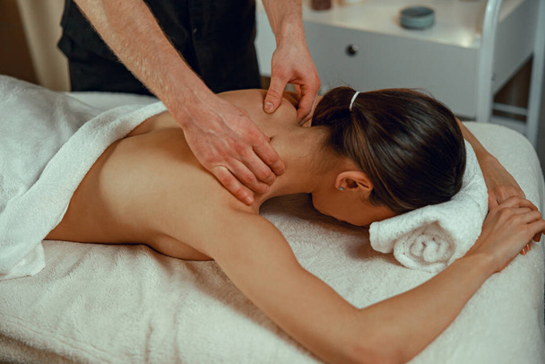 Профессиональный массажист делает массаж спины для клиентки в спа-центре. Расслабление, терапия - Фото, изображение