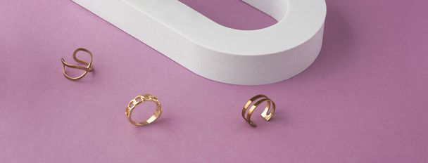 Panorama trzech nowoczesnych pierścieni wzorniczych na białym i fioletowym tle z przestrzenią do kopiowania - Zdjęcie, obraz