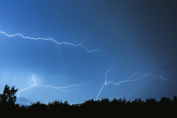 Electrical discharges during a summer storm, branched lightning bolts in the night sky. - Photo, Image