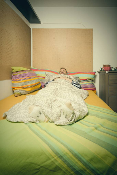 Зрелый больной мужчина заботится о себе в одиночестве дома в постели - Фото, изображение