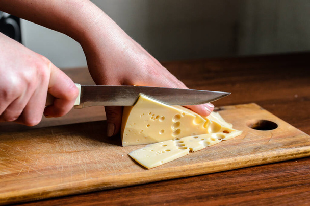 Slicing cheese on a wooden board - Foto, Bild