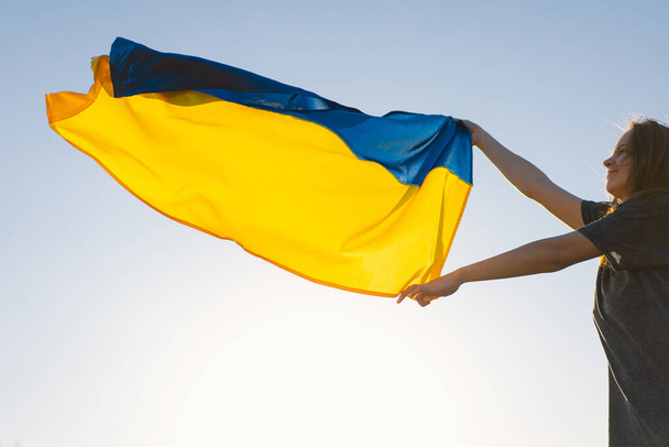 Woman holding a yellow and blue flag of Ukraine in outdoors - 写真・画像