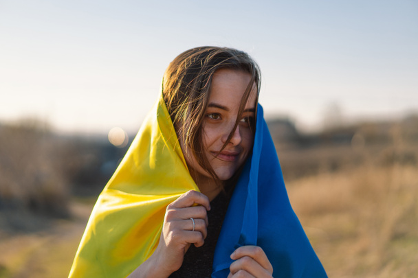 Γυναίκα κρατώντας μια κίτρινη και μπλε σημαία της Ουκρανίας σε εξωτερικούς χώρους - Φωτογραφία, εικόνα
