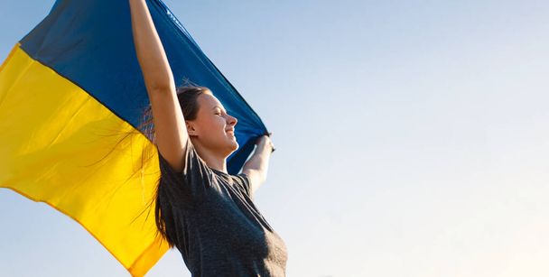 Vrouw met een gele en blauwe vlag van Oekraïne in de buitenlucht - Foto, afbeelding