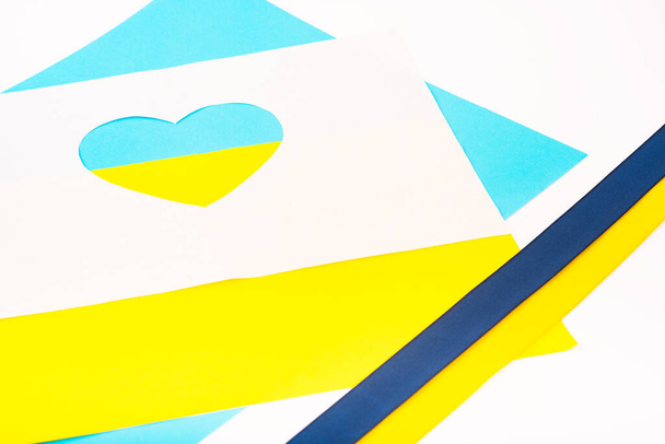 corazón cortado de papel y pintado en colores azules y amarillos y cinta de bandera ucraniana como símbolo de Ucrania. La creatividad como apoyo de Ucrania. La creatividad como apoyo de Ucrania Tendencia colores - Foto, imagen
