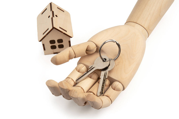 Mão de bonecas de madeira com chaves na palma da mão com casa de madeira de brinquedo isolada em branco - Foto, Imagem