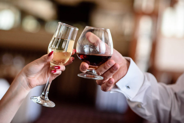Hands holding the glasses of brandy and champagne - Фото, изображение