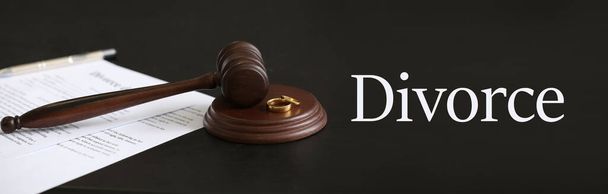 Judge's gavel with wedding rings on dark table. Concept of divorce - Photo, Image