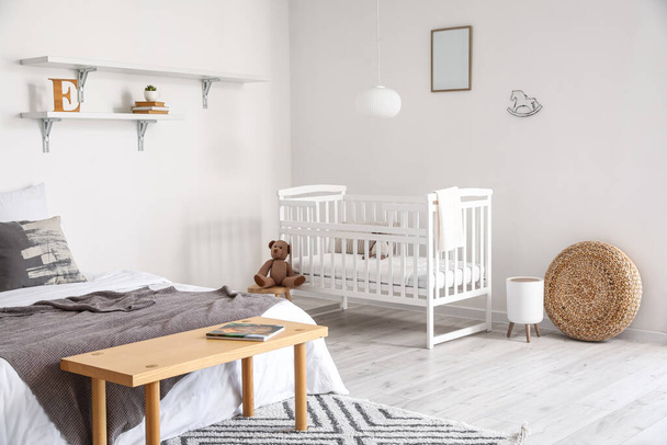 Modern interior of cozy room with big bed and comfortable baby crib - Photo, Image