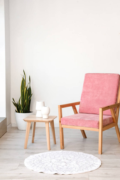 Стильное розовое кресло и стол с вазами в интерьере комнаты - Фото, изображение