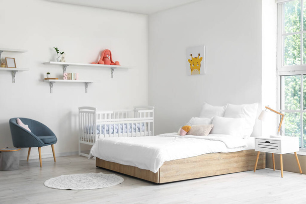 Modern interior of cozy room with big bed and comfortable baby crib - Zdjęcie, obraz
