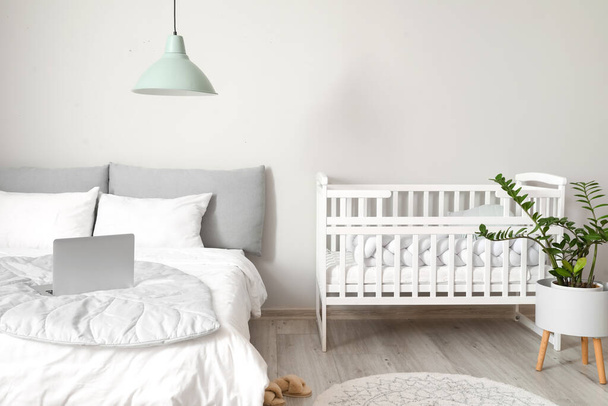 Сучасний інтер'єр затишної кімнати з великим ліжком і зручним дитячим ліжечком
 - Фото, зображення