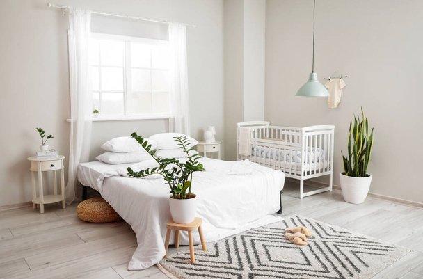 Modern interior of cozy room with big bed and comfortable baby crib - Photo, Image