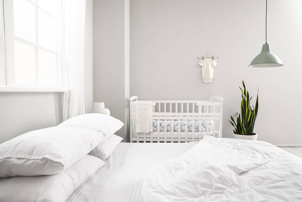 Nagy ágy és kényelmes babaágy a hangulatos szoba belsejében - Fotó, kép