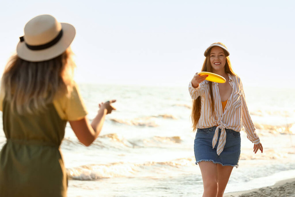 Heureuses jeunes femmes jouant frisbee sur la plage de la mer - Photo, image