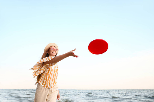Felice giovane donna che gioca frisbee sulla spiaggia di mare - Foto, immagini