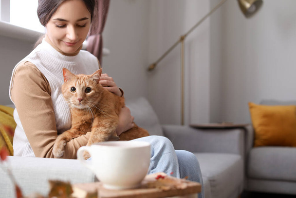 Woman with cute ginger cat at home on autumn day - Foto, afbeelding