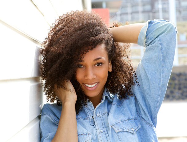 African american woman smiling outdoors with hand in hair - Foto, Imagen