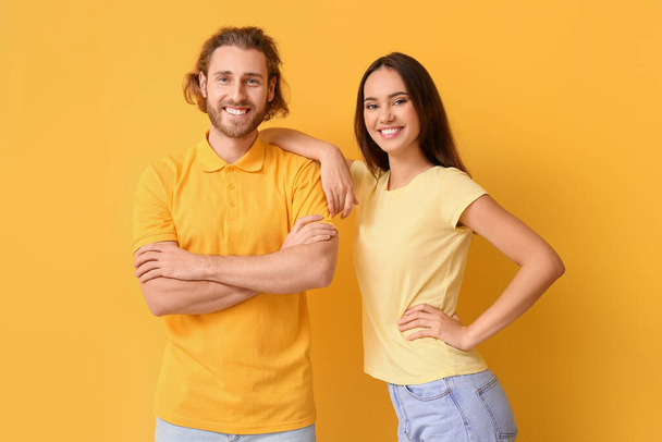 Young couple in stylish t-shirts on yellow background - Photo, Image