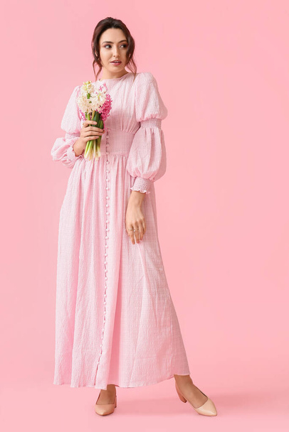 Csinos fiatal nő jácintvirág rózsaszín háttér - Fotó, kép