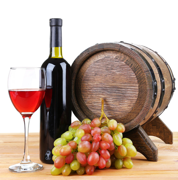 Wine in goblet and in bottle, grapes and barrel on wooden table on white background - Foto, imagen