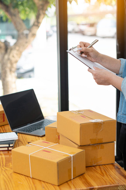 Portrait of a Small Business Startup, Owner, Asian Entrepreneur Working on boxes and laptops, checking online orders to prepare boxes. Selling to customers, SME business concept, online sales name - Фото, изображение