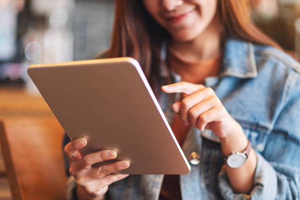 Güzel bir genç kadının tablet bilgisayarını tutarken ve kullanırken yakın plan görüntüsü. - Fotoğraf, Görsel