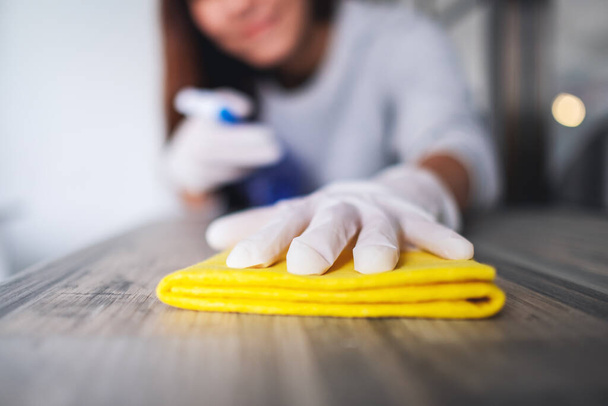 Młoda kobieta w rękawiczce ochronnej sprzątająca stół do prac domowych - Zdjęcie, obraz