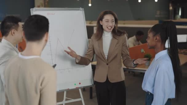 Happy smiling multiethnic group of business people clapping to young leader manager after presentation on flip chart in office room. Business, finance, sales, success. - Footage, Video