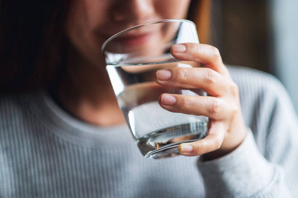 Closeup image of a beautiful young asian woman holding a glass of water to drink - Foto, imagen
