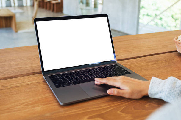 Immagine mockup di una donna che utilizza e tocca il touchpad del computer portatile con schermo bianco vuoto sul tavolo di legno - Foto, immagini