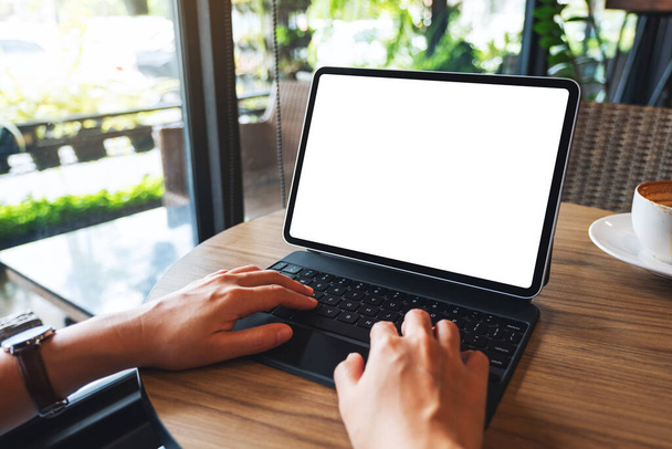 Imagen burlona de una mujer usando y escribiendo en el teclado de la tableta con la pantalla blanca en blanco del escritorio como una PC de la computadora en la tabla - Foto, imagen