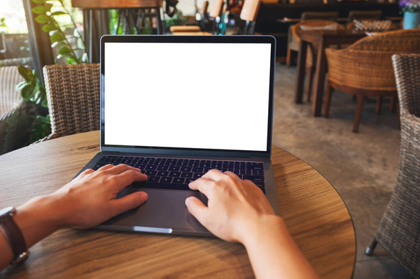 Immagine mockup di una donna che utilizza e digita sulla tastiera del computer portatile con schermo bianco vuoto sul tavolo di legno - Foto, immagini