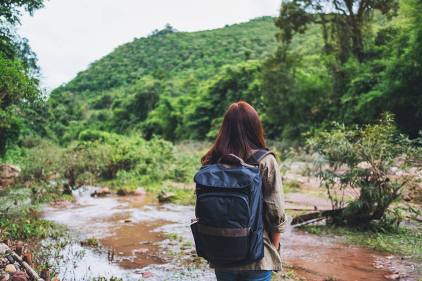 Hátsó nézet egy női utazó hátizsákkal séta a hegyi patak a túra koncepció - Fotó, kép