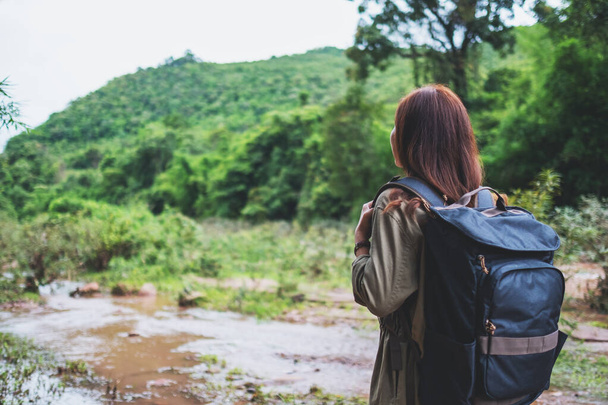 Imagem da visão traseira de uma viajante feminina com mochila andando pelo córrego da montanha para conceito de caminhada - Foto, Imagem