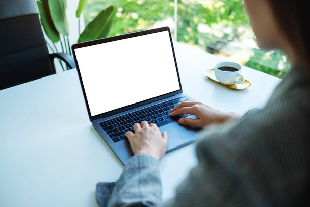 Mockup obrazu businesswoman za pomocą i wpisując na klawiaturze laptopa z pustym białym ekranem pulpitu w biurze - Zdjęcie, obraz