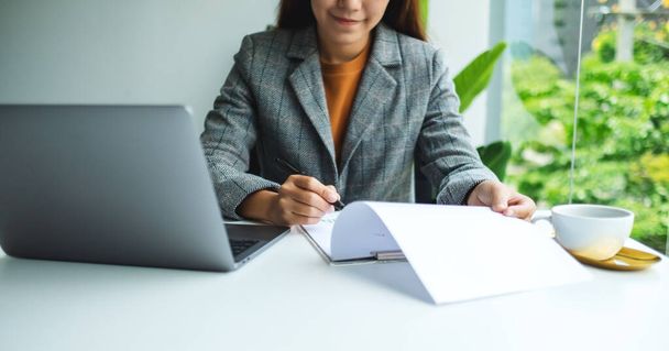 Imprenditrice che lavora ai documenti aziendali e al computer portatile in ufficio - Foto, immagini