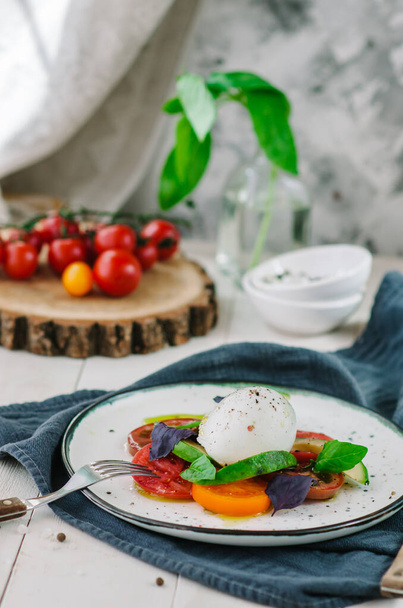 Buffalo burrata cheese served with fresh raw tomatoes and basil leaves - Foto, Imagen