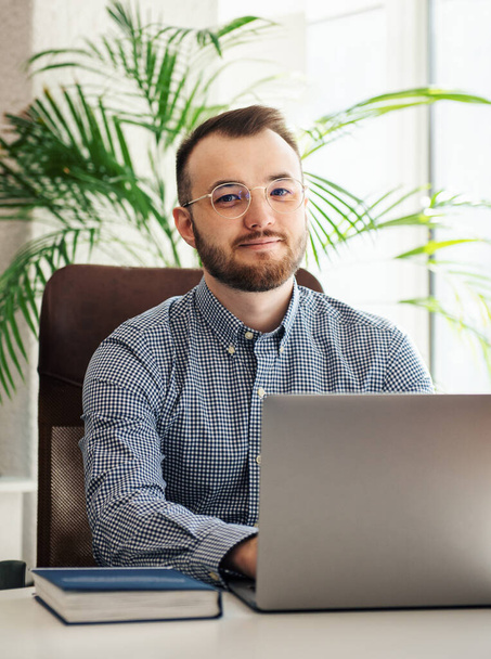 Giovane uomo d'affari in camicia che lavora sul suo computer portatile in un ufficio - Foto, immagini