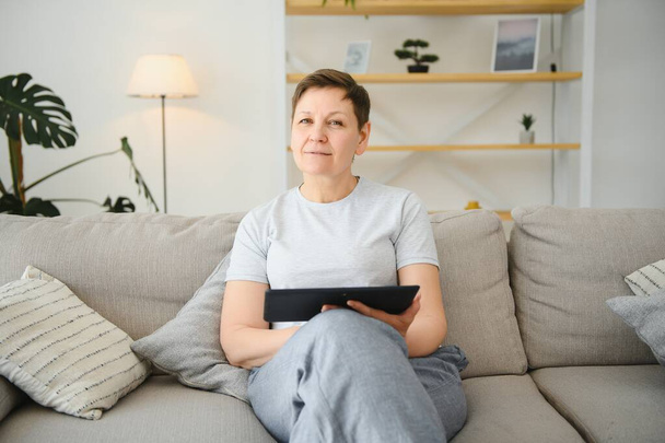 people, technology and internet concept - happy middle aged woman with tablet pc computer at home - Valokuva, kuva