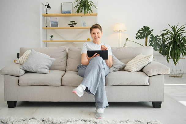 people, technology and internet concept - happy middle aged woman with tablet pc computer at home - Foto, Bild