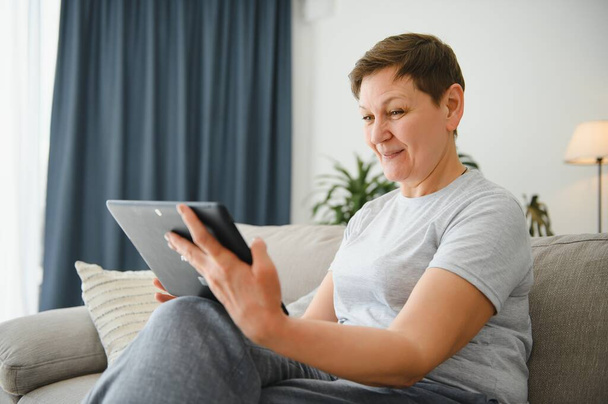 mature middle aged adult woman holding digital tablet computer conference calling by social distance virtual family online chat meeting. - Foto, Bild