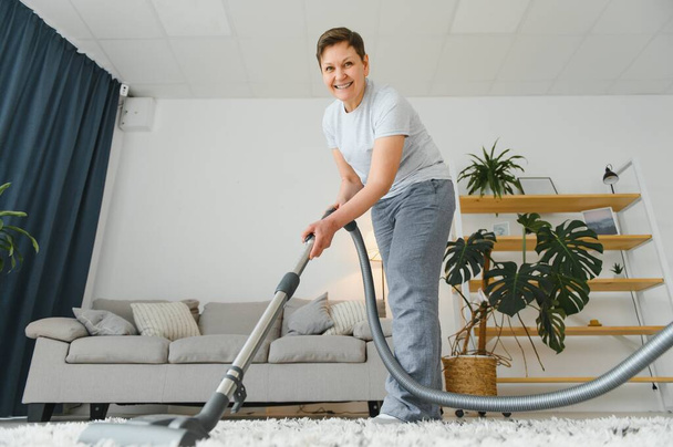 Cleaning concept. woman cleaning carpet with vacuum cleaner - Foto, afbeelding