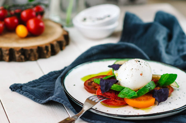 Buffalo burrata cheese served with fresh raw tomatoes and basil leaves - Foto, Imagen