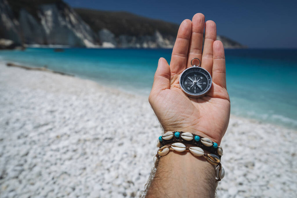 Hand holding a compass on the beach in background. - Zdjęcie, obraz
