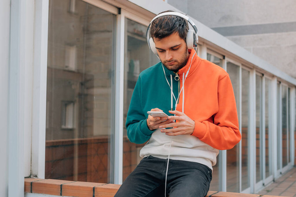 young man in the street with mobile phone and headphones - Photo, Image