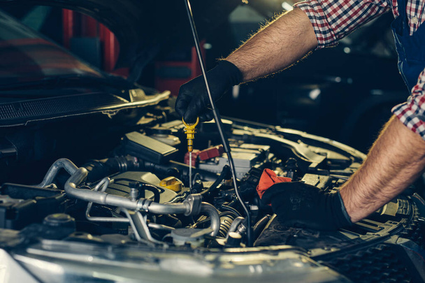 Car mechanic checking oil level in a mechanical workshop - Фото, зображення