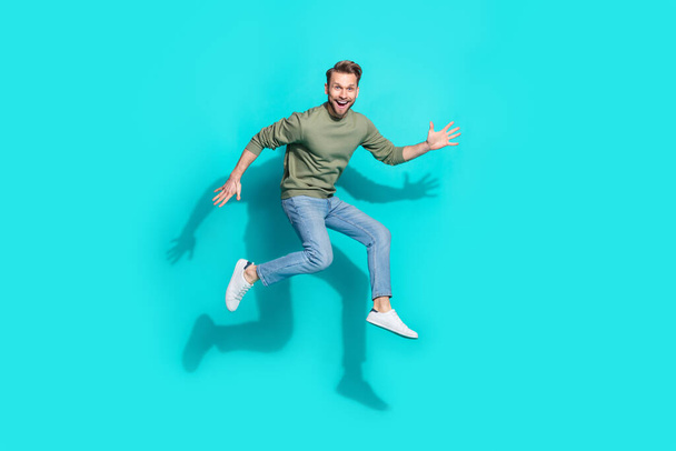 Full size photo of millennial blond guy jump wear sweater jeans sneakers isolated on turquoise background - Foto, Imagen