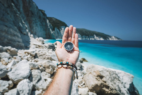 Hand holding a compass on the beach in background. - Foto, Imagem