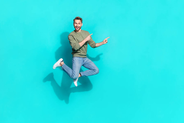 Full size photo of millennial blond guy jump index promo wear sweater jeans shoes isolated on teal background - 写真・画像